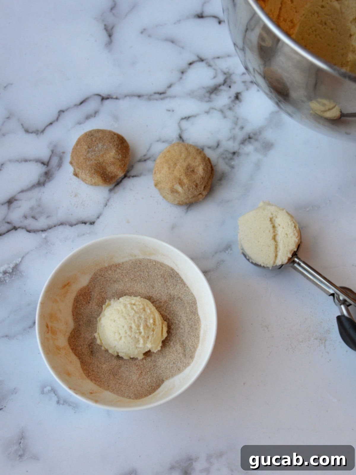 A ball of gluten-free cookie dough perfectly coated in cinnamon sugar, ready for baking