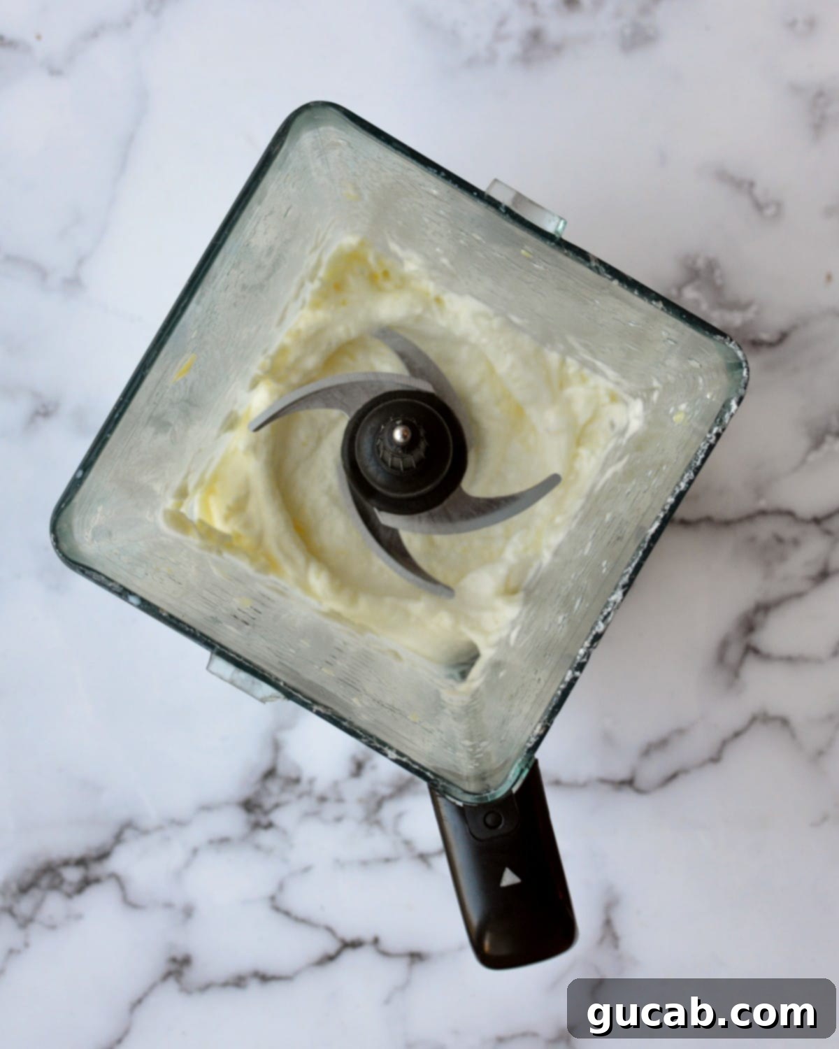 Close-up shot of a blender with a thick, creamy pineapple mixture, already blended smoothly.