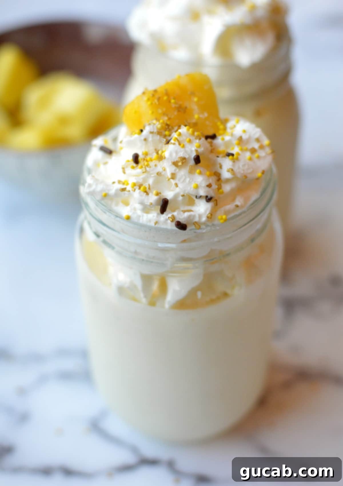 A pineapple milkshake topped with whipped cream and a pineapple wedge, ready to be enjoyed.