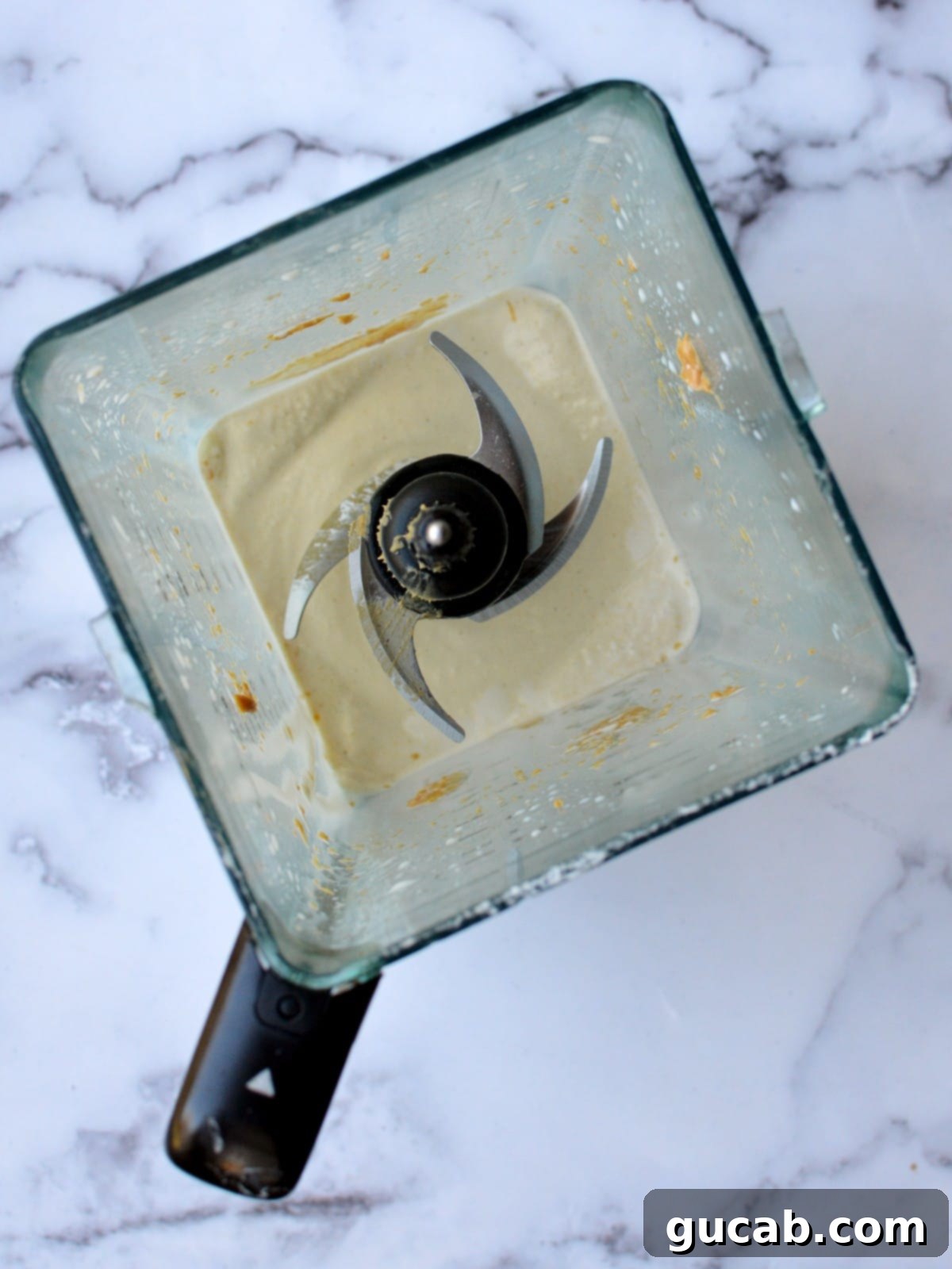 A high-speed blender actively mixing the ingredients into a thick, frothy peanut butter milkshake.
