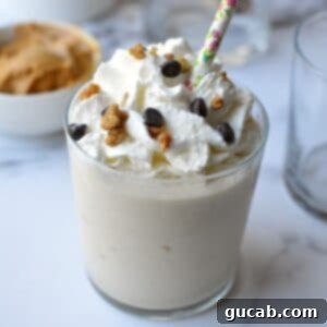 A tall glass of indulgent peanut butter milkshake, garnished with whipped cream and a drizzle of chocolate sauce.