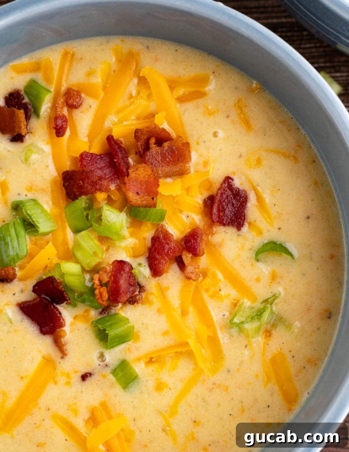 close up of potato soup with bacon, cheese, and chives on top. 