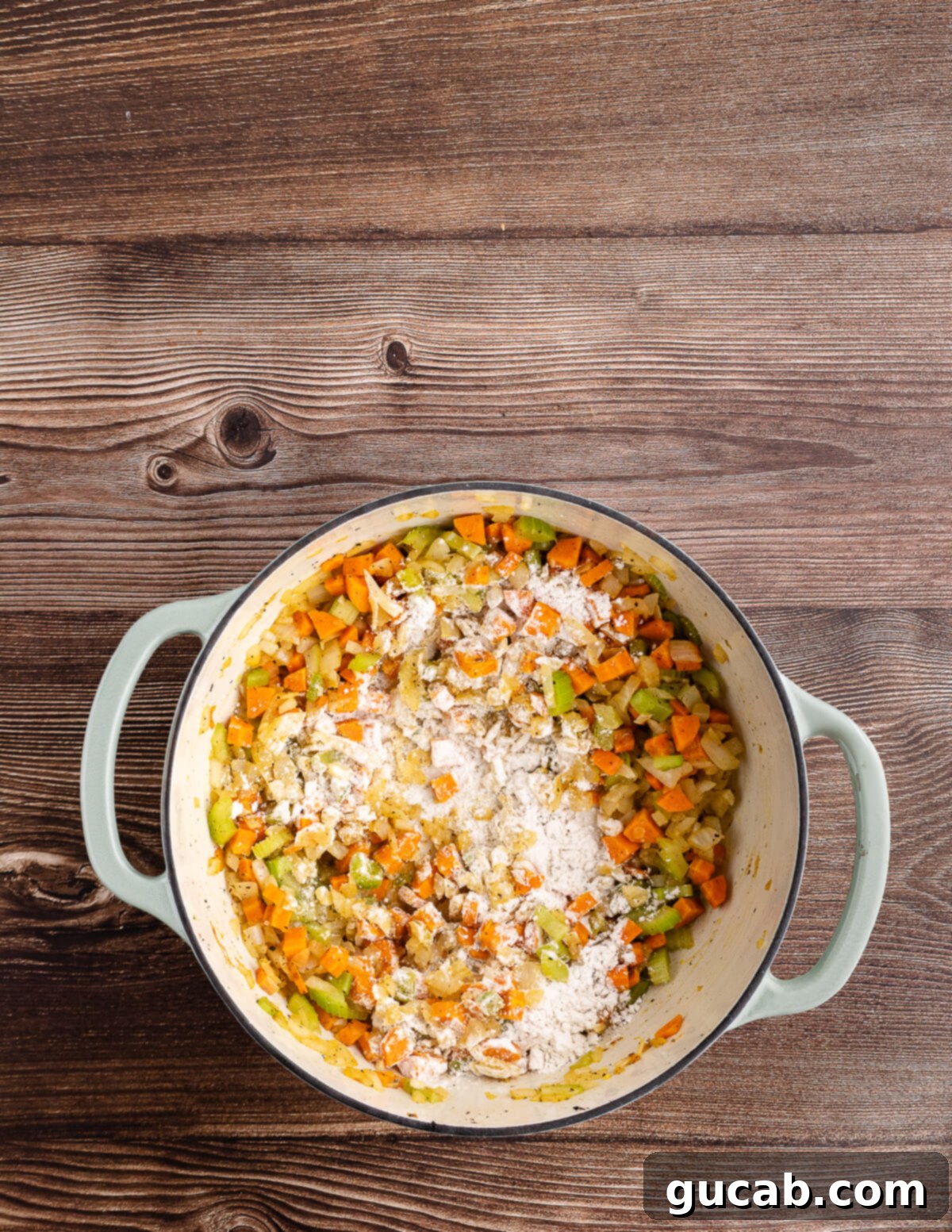 sauteed veggies in a dutch oven with gluten-free flour on top