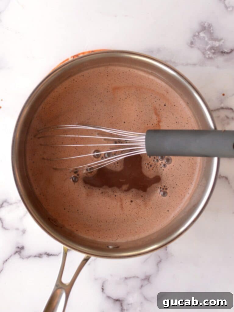 Velvety Oat Milk Hot Chocolate 7 Creamy oat milk hot chocolate in a saucepan after the chocolate has melted, showing a smooth and rich texture