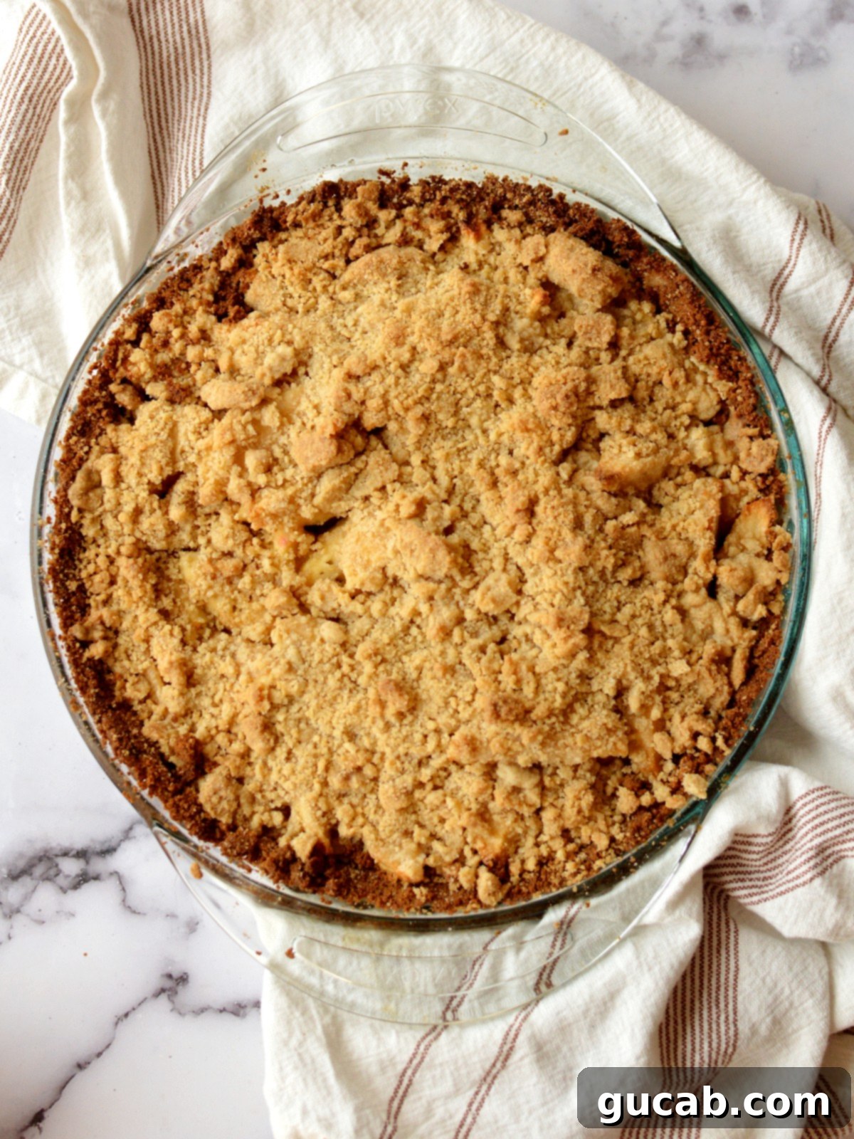 A beautifully baked apple pie with a golden graham cracker crust and a streusel topping, ready to be served.