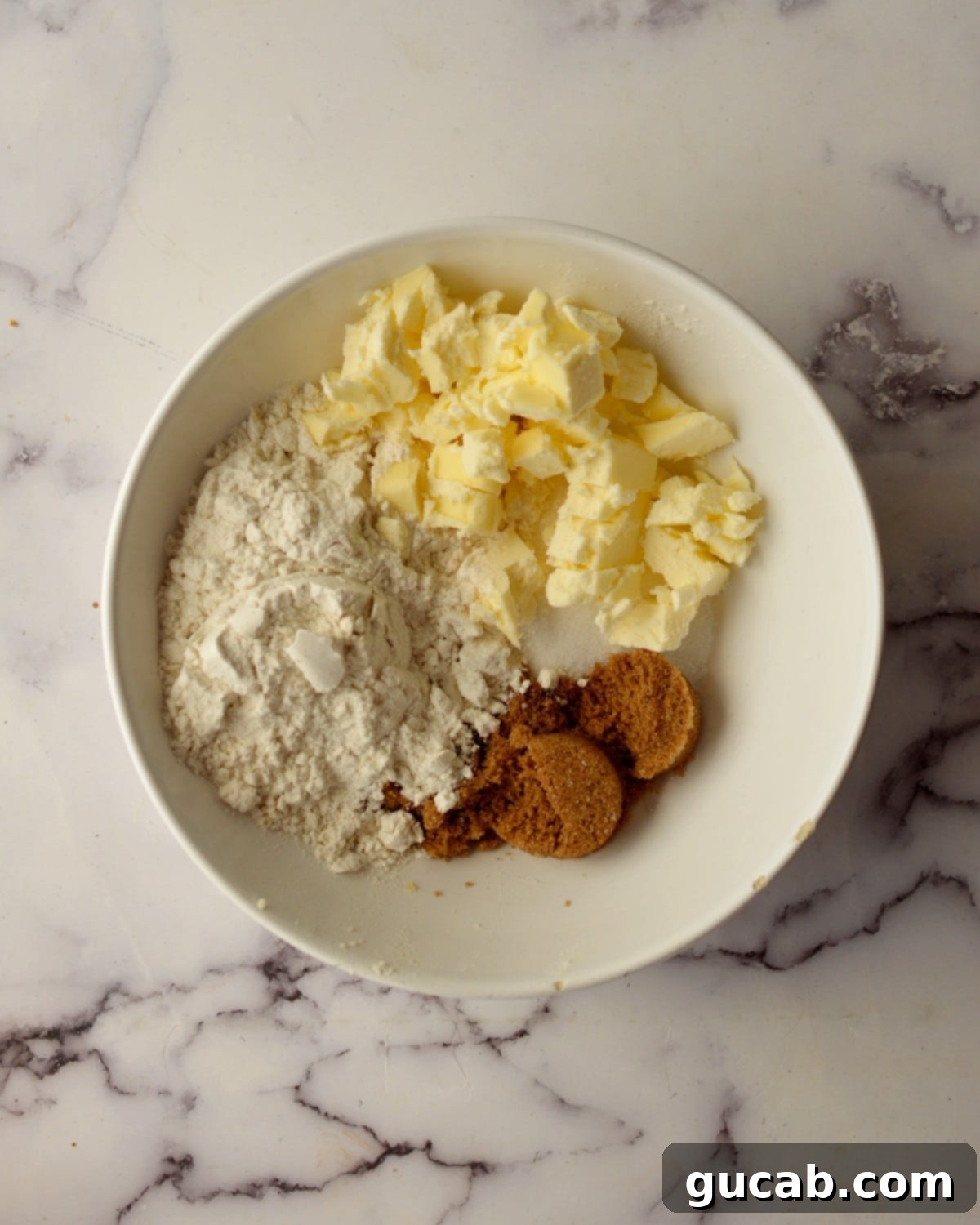Cold butter pieces, all-purpose flour, rich brown sugar, and sparkling white sugar, ready to be combined for a delicious crumb topping.