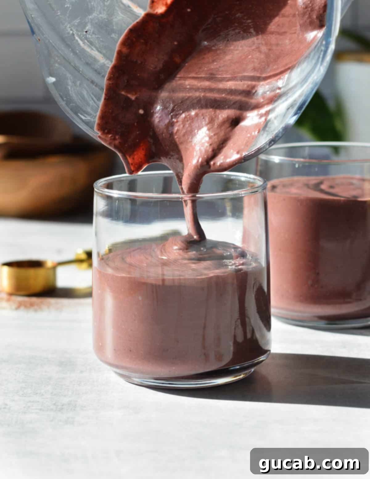 Chocolate Berry Bliss 6 pouring a chocolate smoothie into a glass.