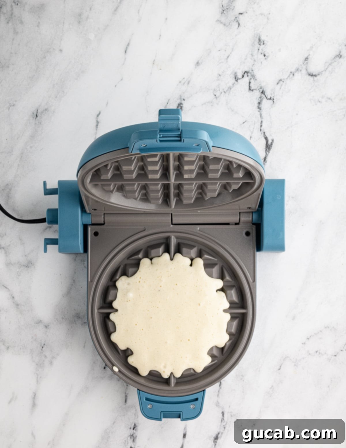 Your New Favorite Gluten-Free Waffle Recipe 13 Fresh gluten-free waffle batter poured into a hot waffle iron, just beginning to cook and expand.