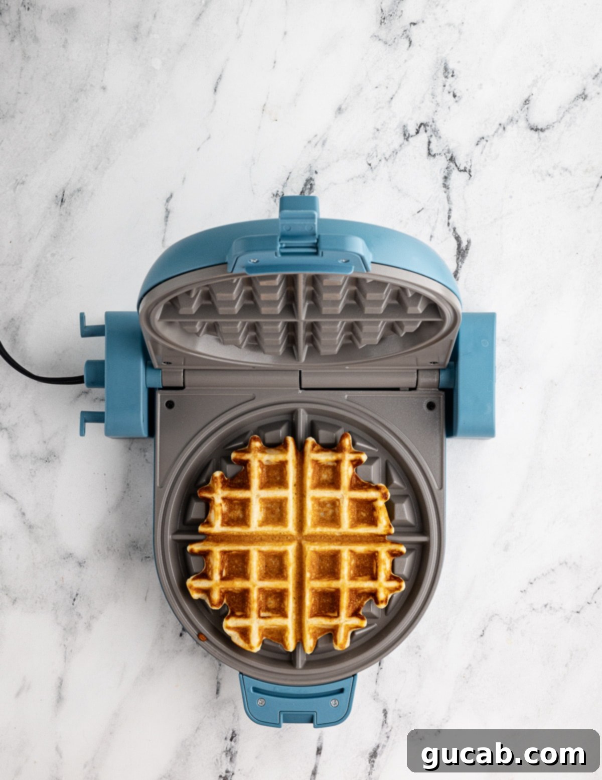 Your New Favorite Gluten-Free Waffle Recipe 14 A perfectly cooked golden-brown gluten-free waffle sitting in an open waffle iron, steam gently rising.