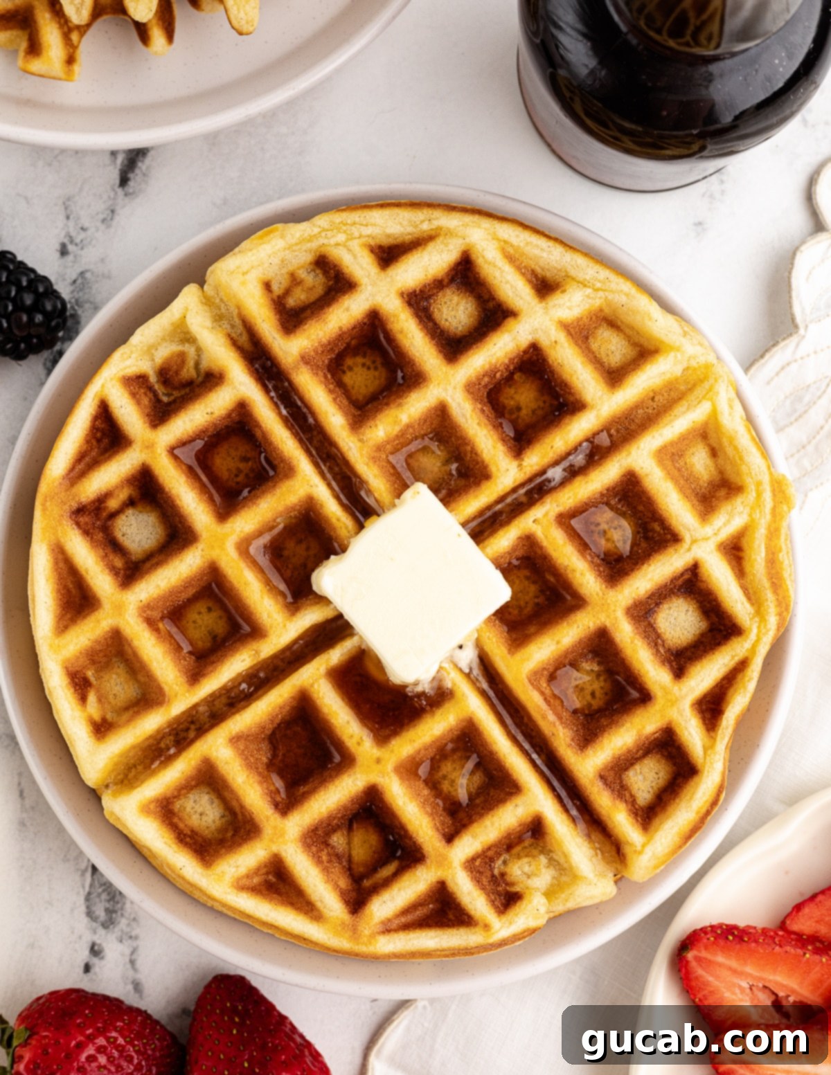 A single perfectly golden-brown gluten-free waffle resting on a white plate, with a pat of butter melting invitingly in its center.
