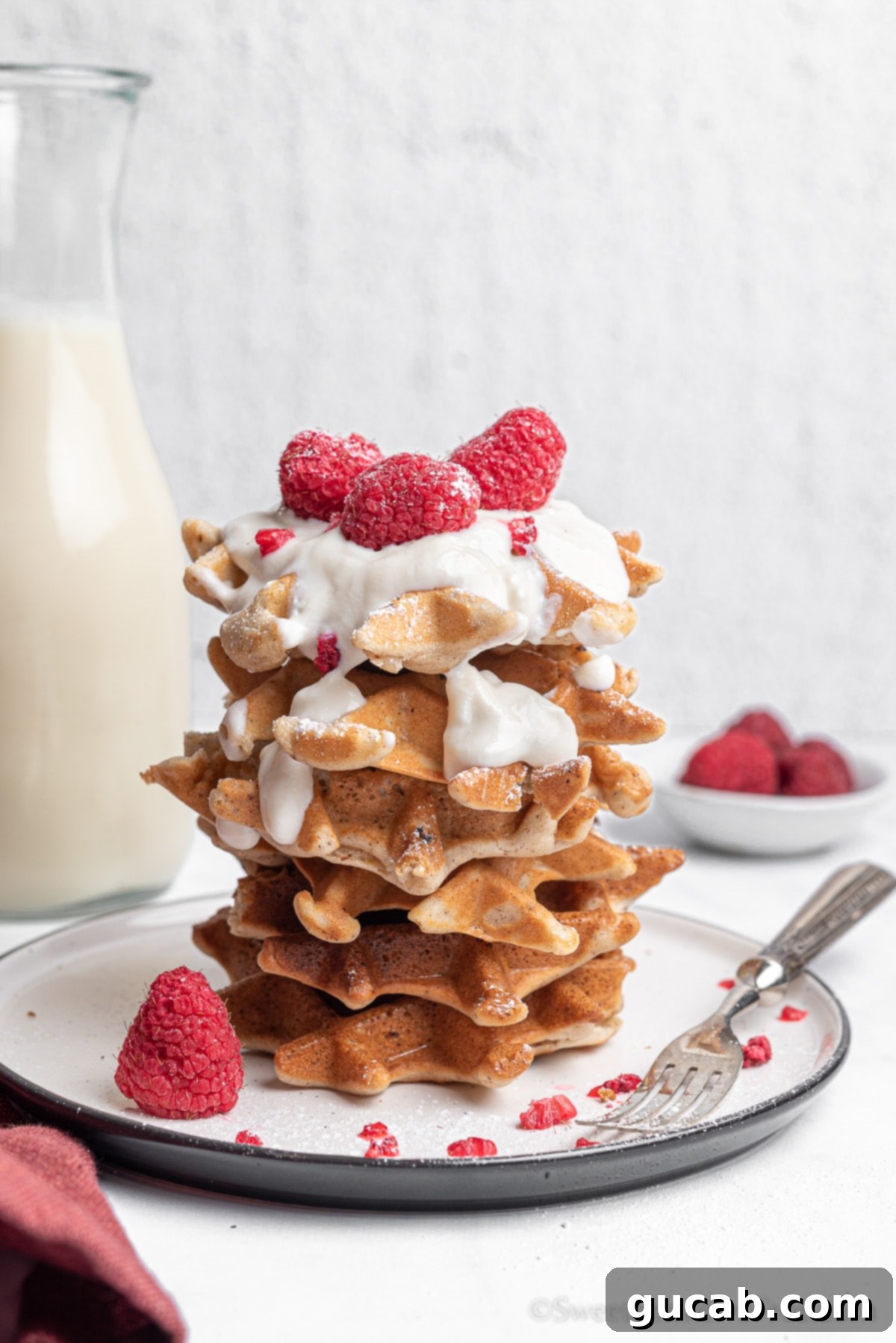 a stack of vegan waffles topped with fresh fruit and coconut whipped cream, a perfect gluten-free and dairy-free breakfast