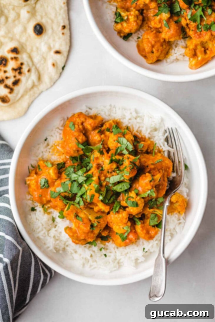 cauliflower in curry sauce on top of rice, a delicious vegan butter chicken alternative
