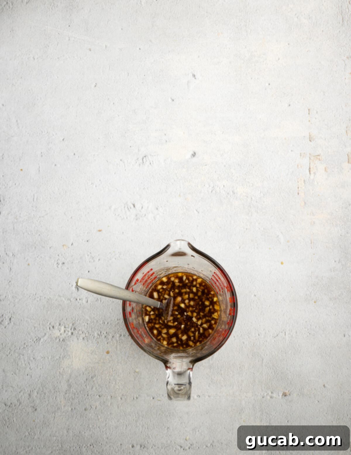 A liquid measuring cup filled with the prepared stir fry sauce ingredients, including soy sauce, garlic, chicken broth, brown sugar, and sesame oil, ready to be mixed.