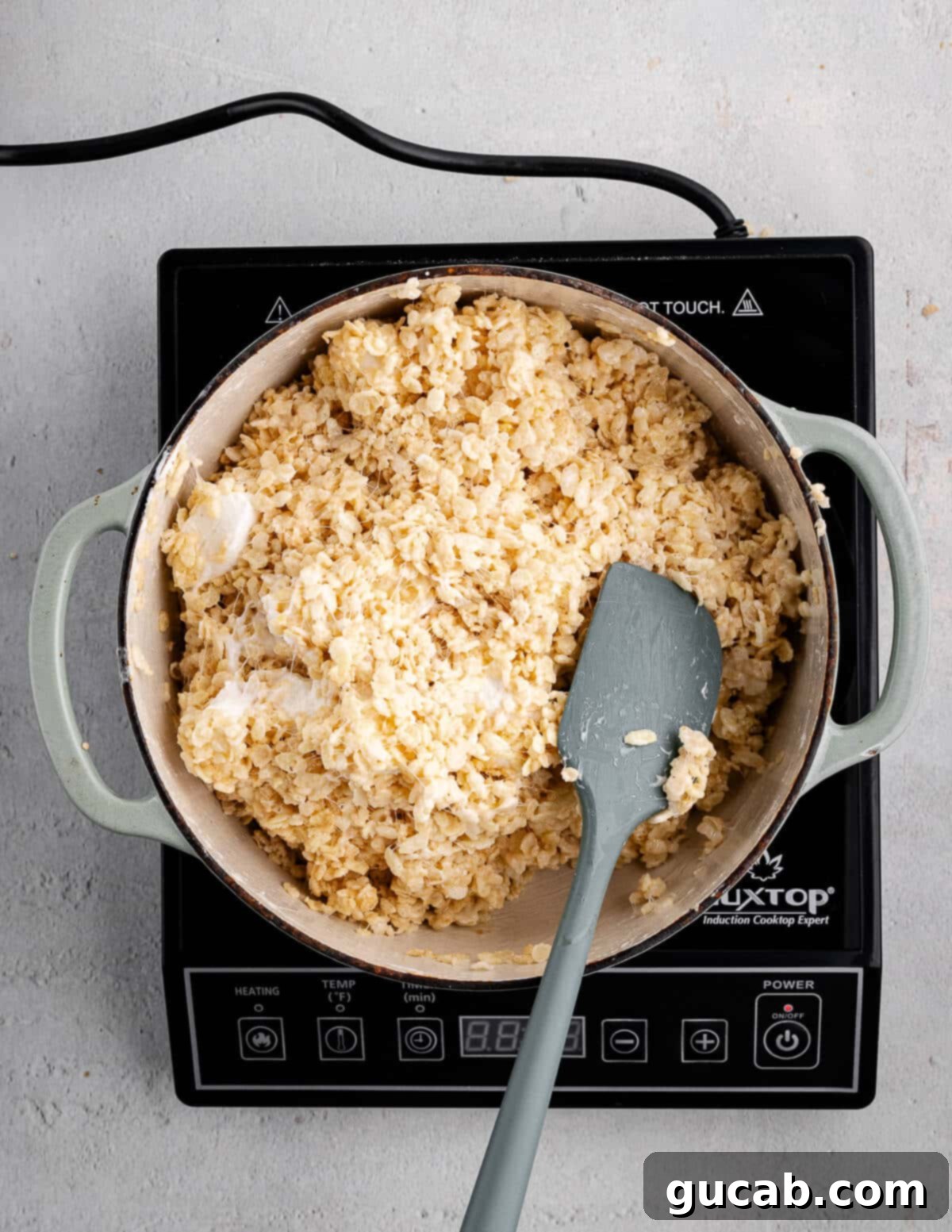 A dutch oven with the sticky rice crispy mixture, showing large marshmallow chunks evenly dispersed.
