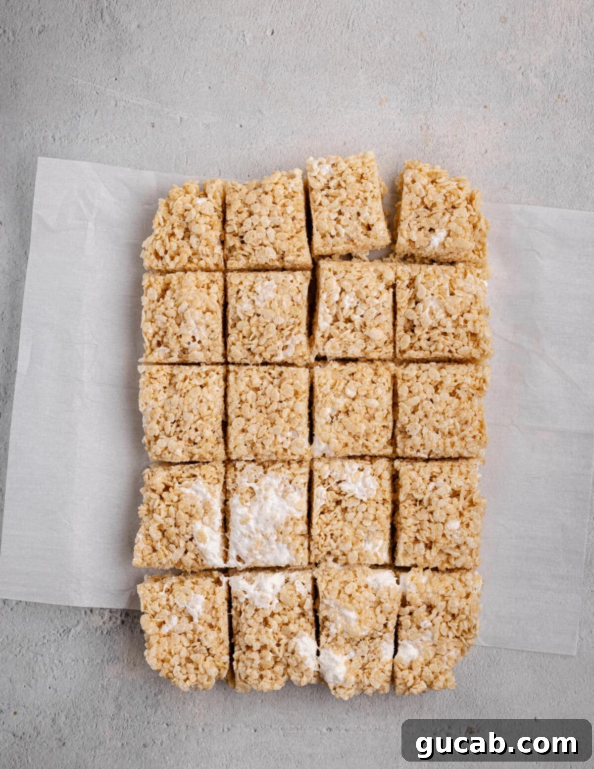 Homemade cut rice krispie bars neatly arranged on parchment paper, ready to serve.