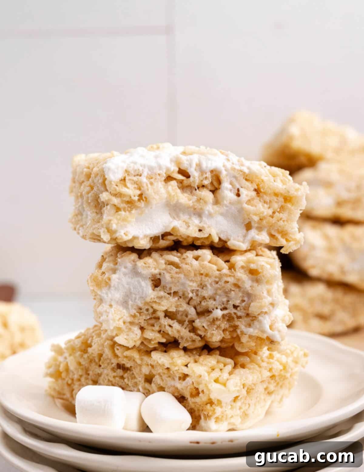 A neat stack of golden homemade rice krispie treats on a rustic surface, showcasing their delicious texture. 