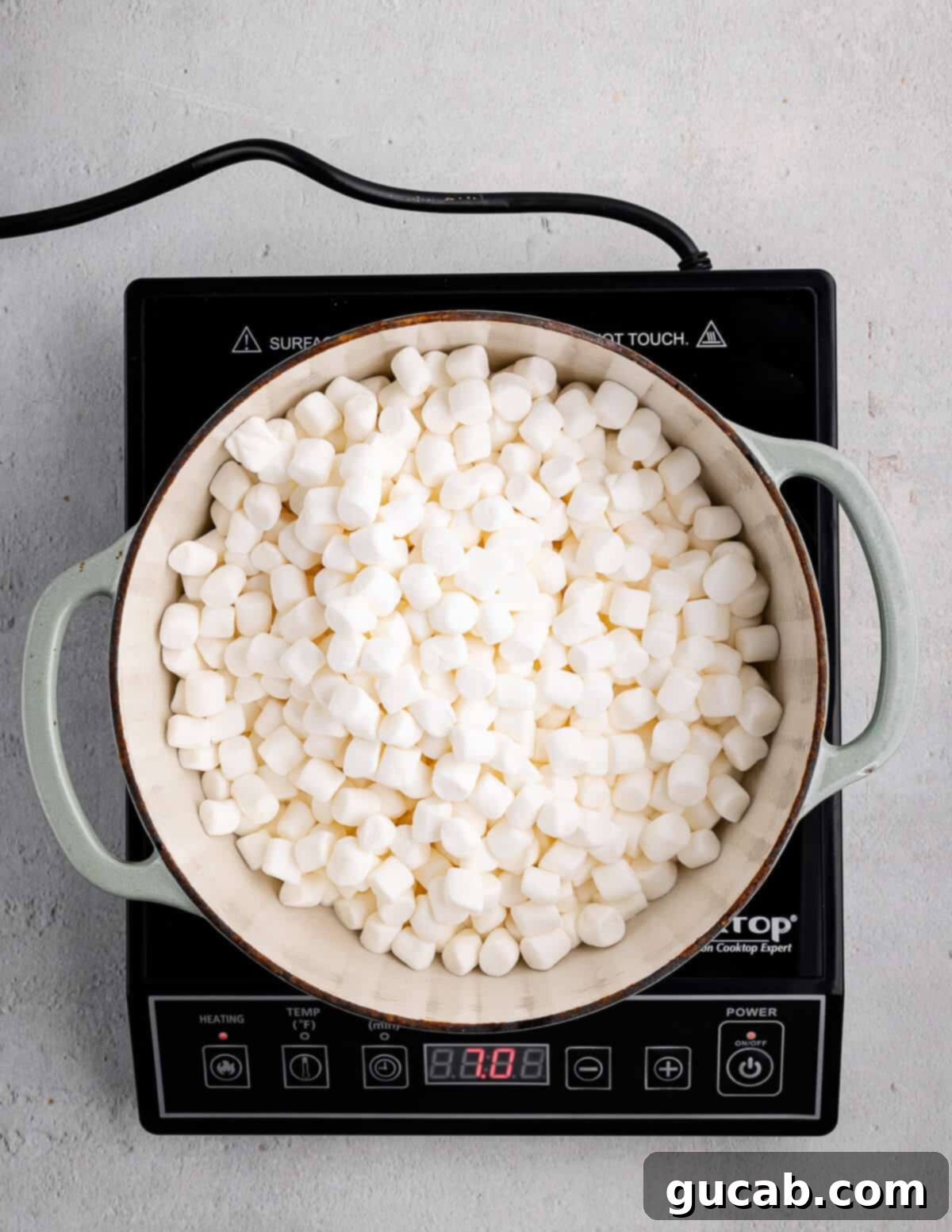 A dutch oven with mini marshmallows just added, beginning to melt.
