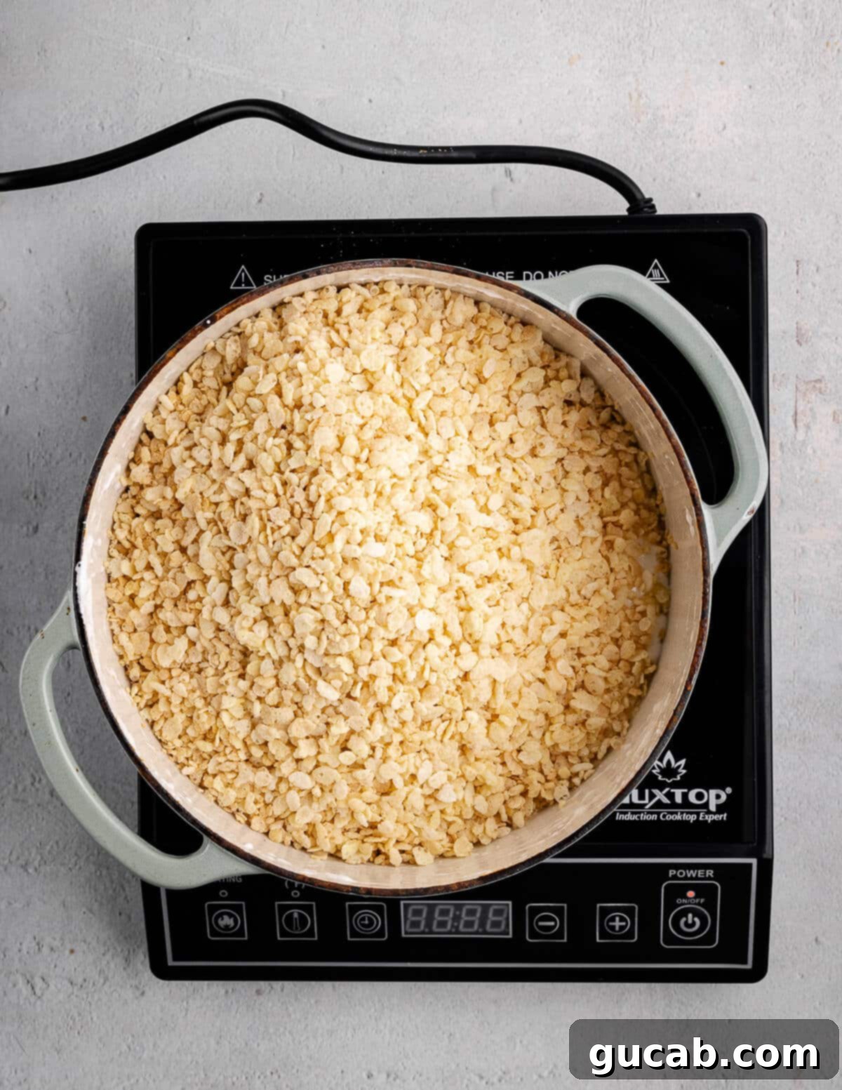 A dutch oven with dry rice krispies cereal just added to the melted marshmallow mixture.