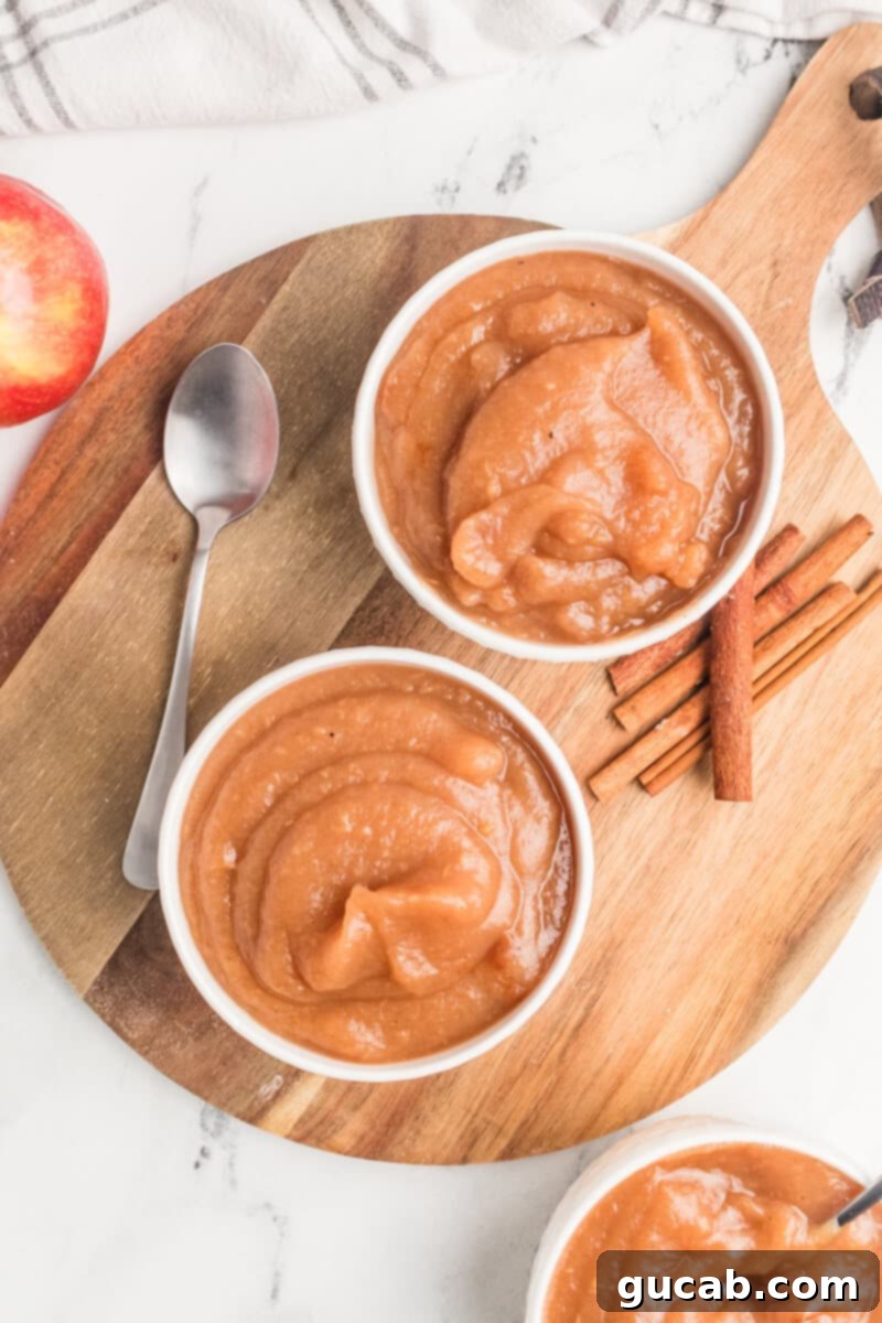 Three small glass bowls filled with warm, homemade applesauce, arranged artfully for serving.