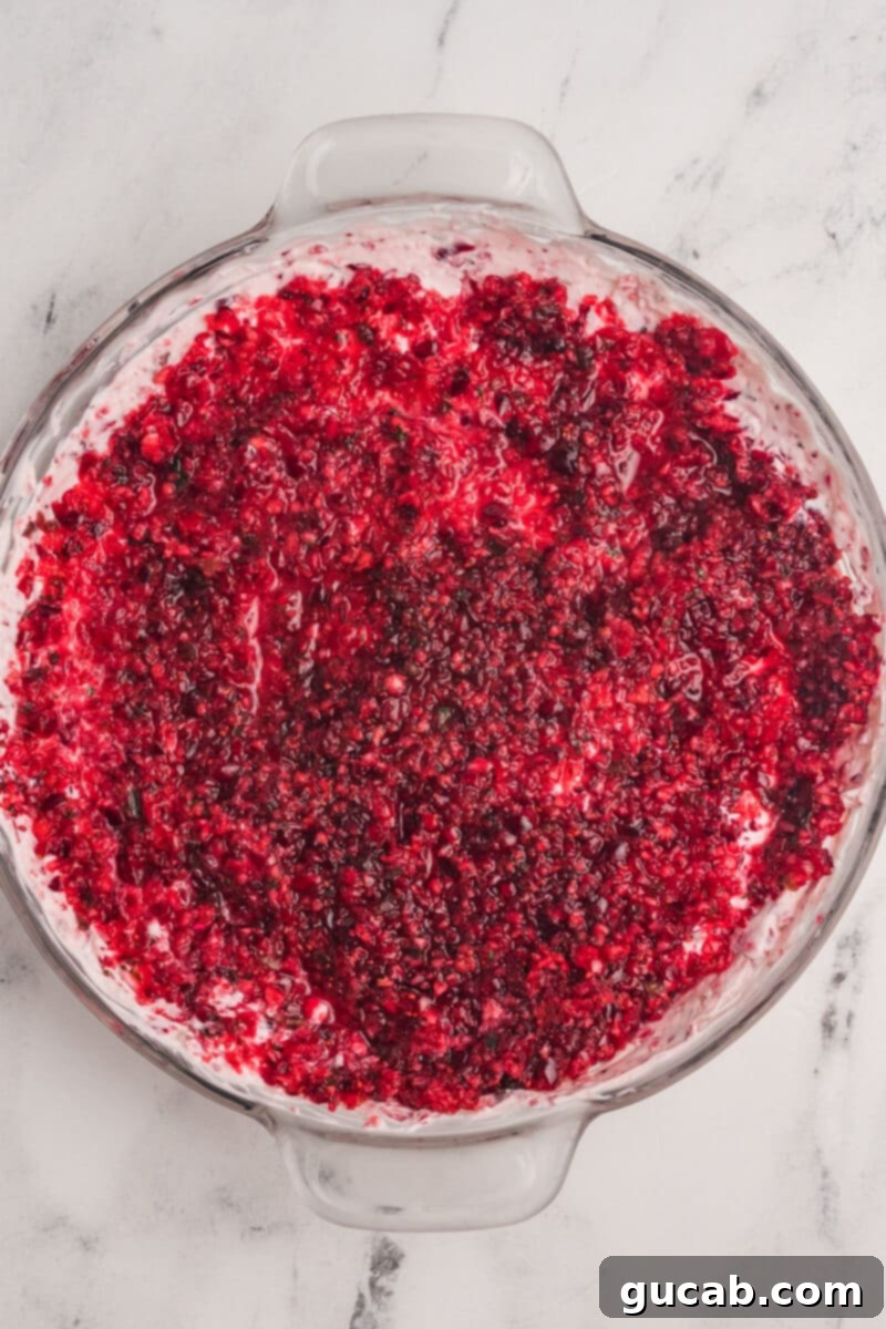 The finished cranberry jalapeno cream cheese dip, beautifully presented with a thick layer of red chutney over a creamy base, showcasing its festive appeal.