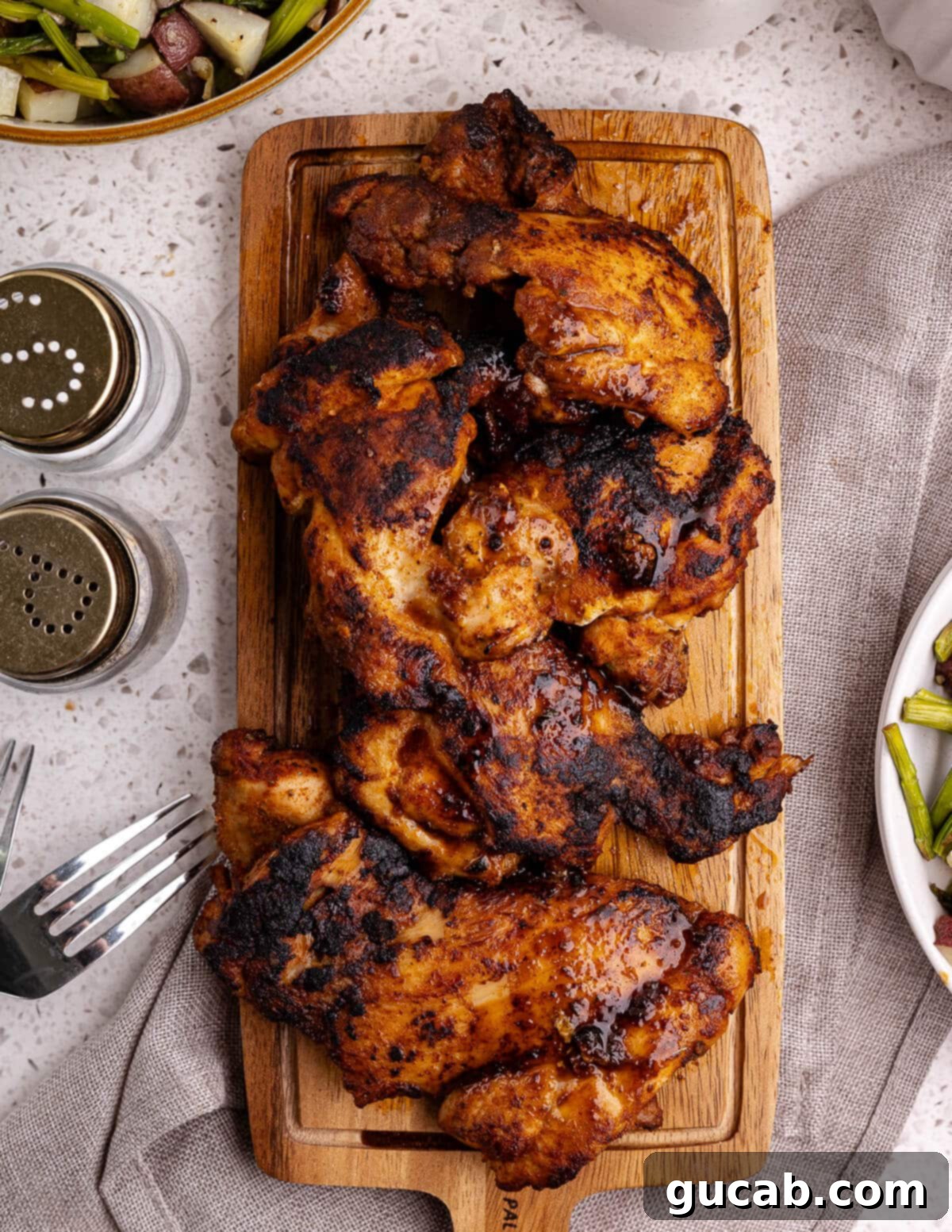 Perfectly Baked Boneless Skinless Chicken Thighs 2 cooked boneless skinless chicken thighs on a cutting board.