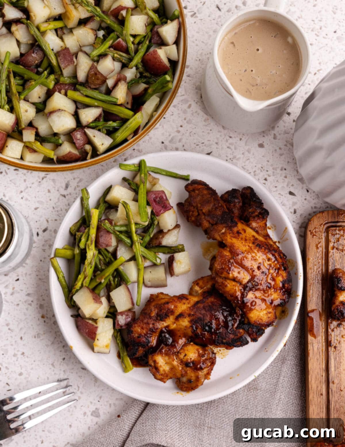 Perfectly Baked Boneless Skinless Chicken Thighs 10 roasted potatoes and asparagus with caramelized chicken on a plate.