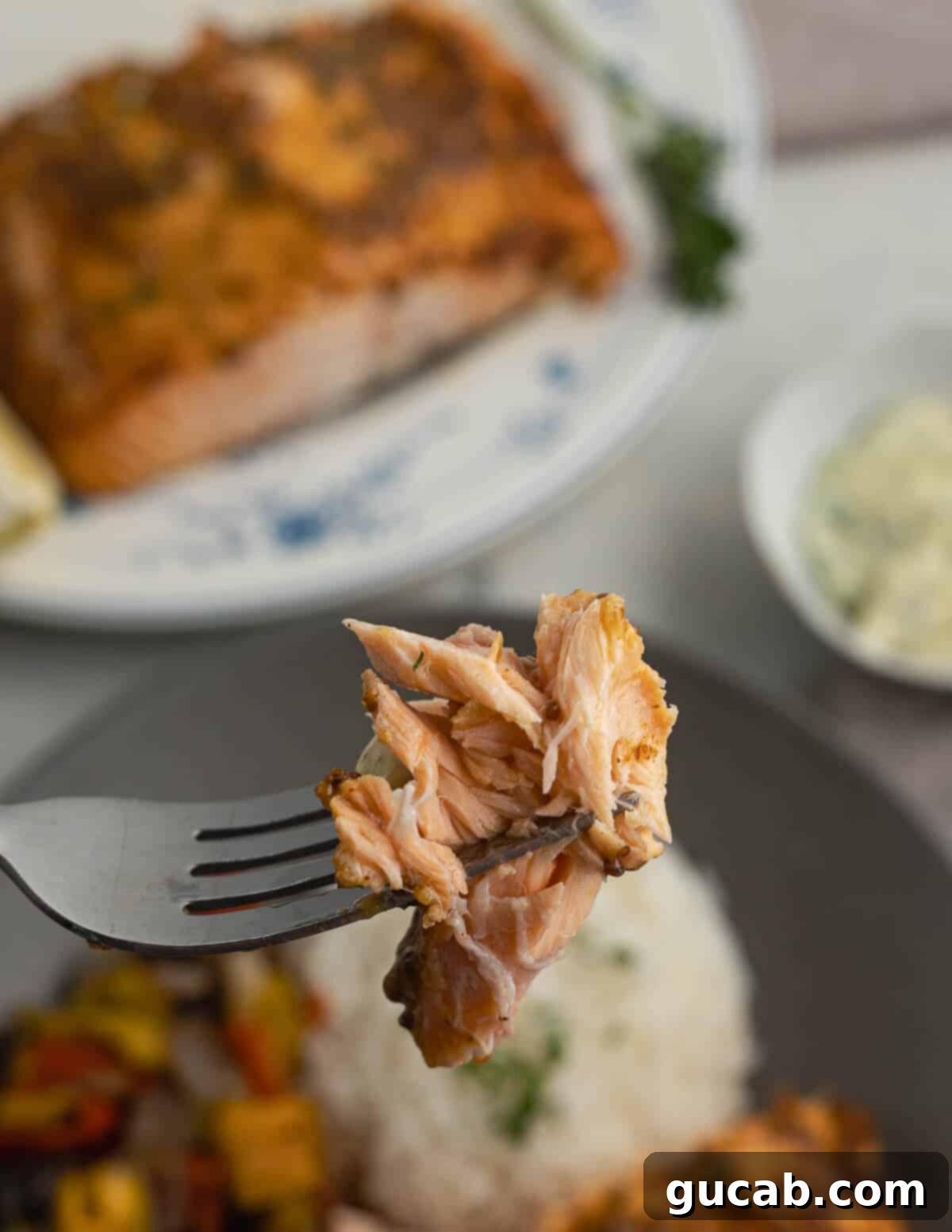 A forkful of perfectly cooked, flaky toaster oven salmon, showcasing its tender texture and appealing color.