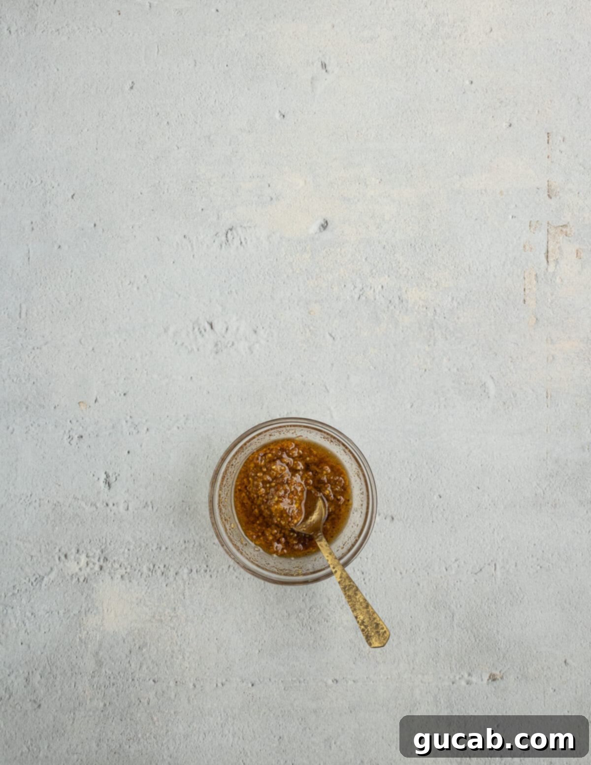 Grainy mustard, olive oil, and a variety of spices are mixed together in a small bowl, ready to be used as a flavorful marinade for the salmon.