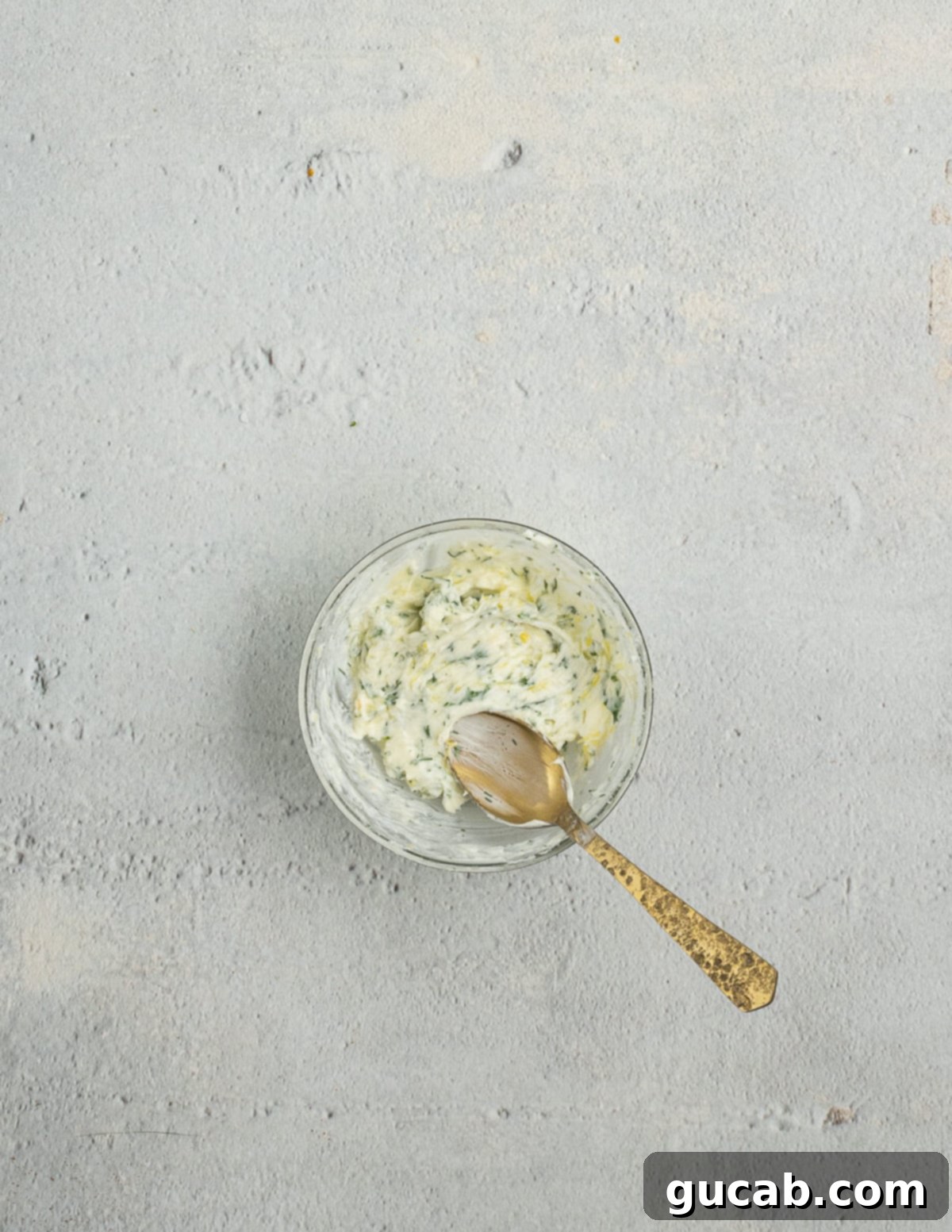 A bowl filled with fragrant lemon herb butter, showcasing its vibrant color and creamy texture.