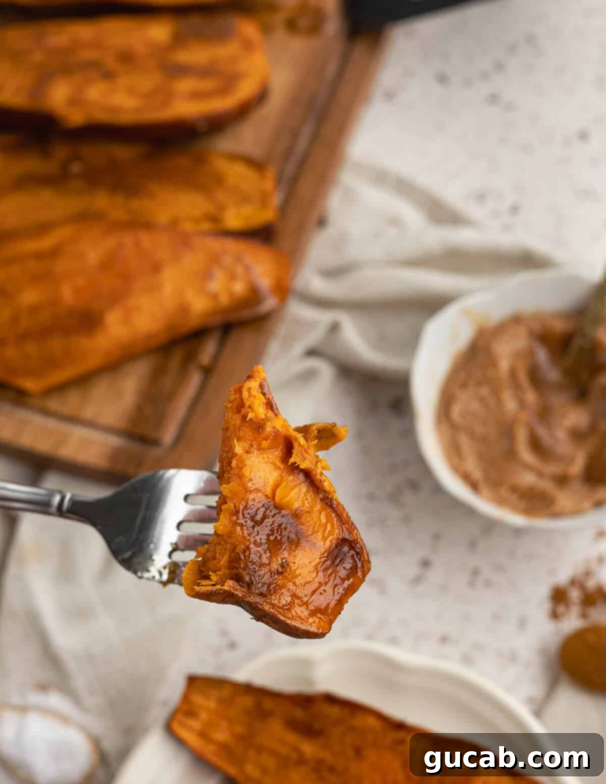 A close-up shot of a forkful of baked sweet potato, showcasing its tender interior and slightly caramelized exterior.
