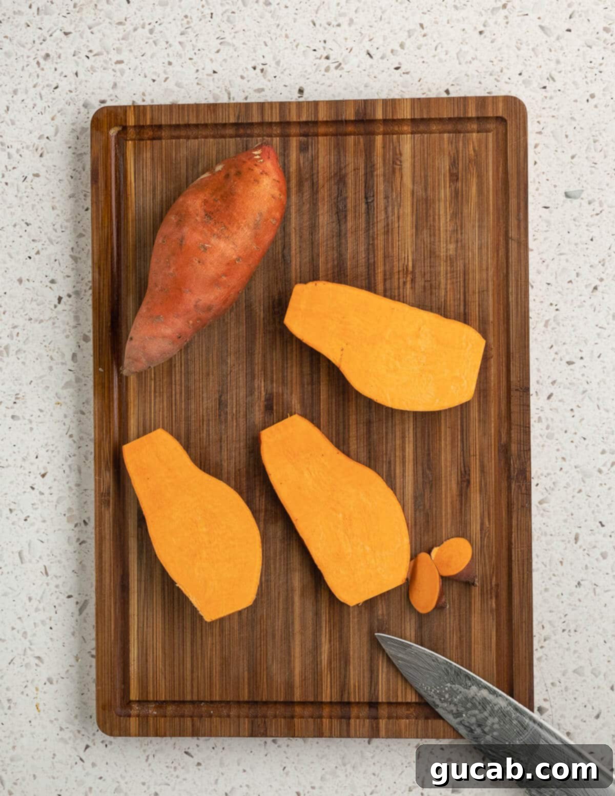 Close-up of sliced sweet potatoes arranged neatly on a wooden cutting board, ready for baking.