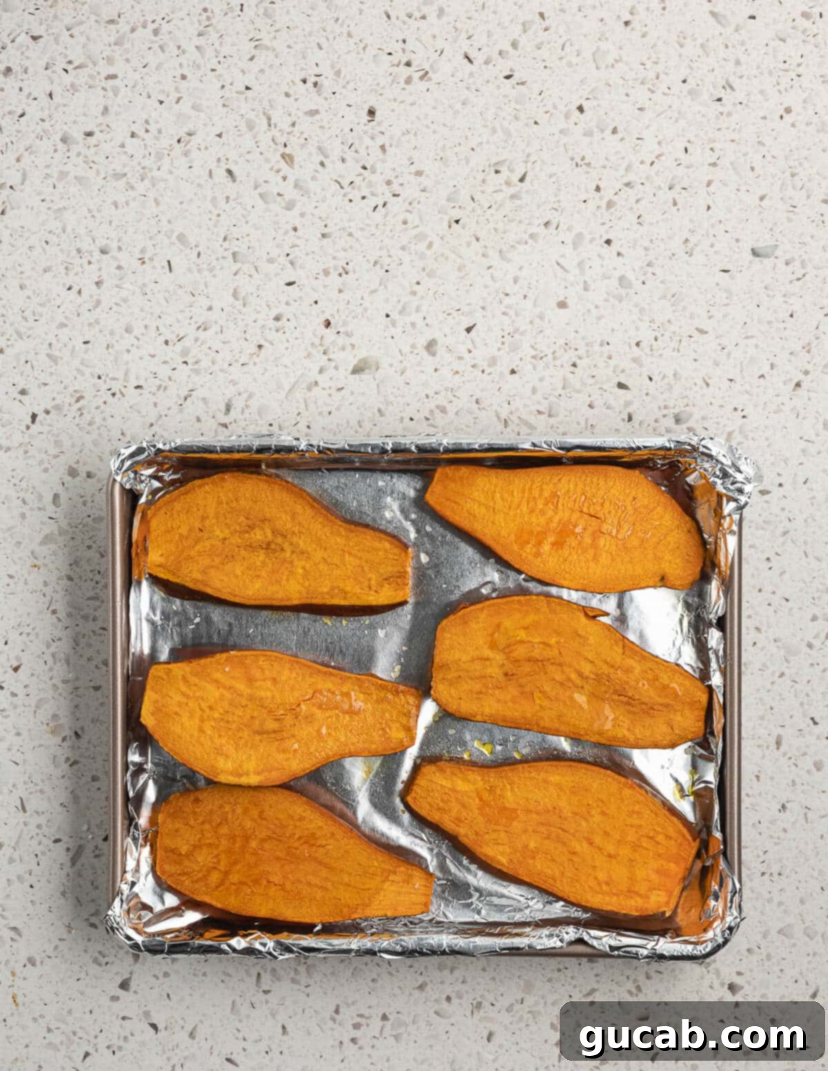 The baked sweet potato slices are now golden brown and slightly caramelized on a sheet pan, indicating they are perfectly cooked.