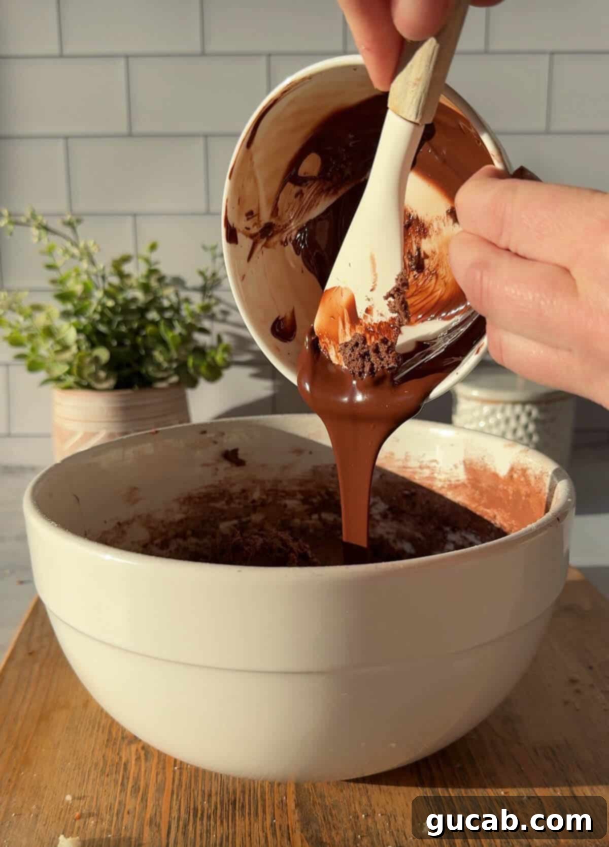 Oat Flour Double Chocolate Chunk Cookies 6 A close-up view of melted chocolate being carefully scraped into a bowl of cookie dough, highlighting the addition of intense chocolate flavor.