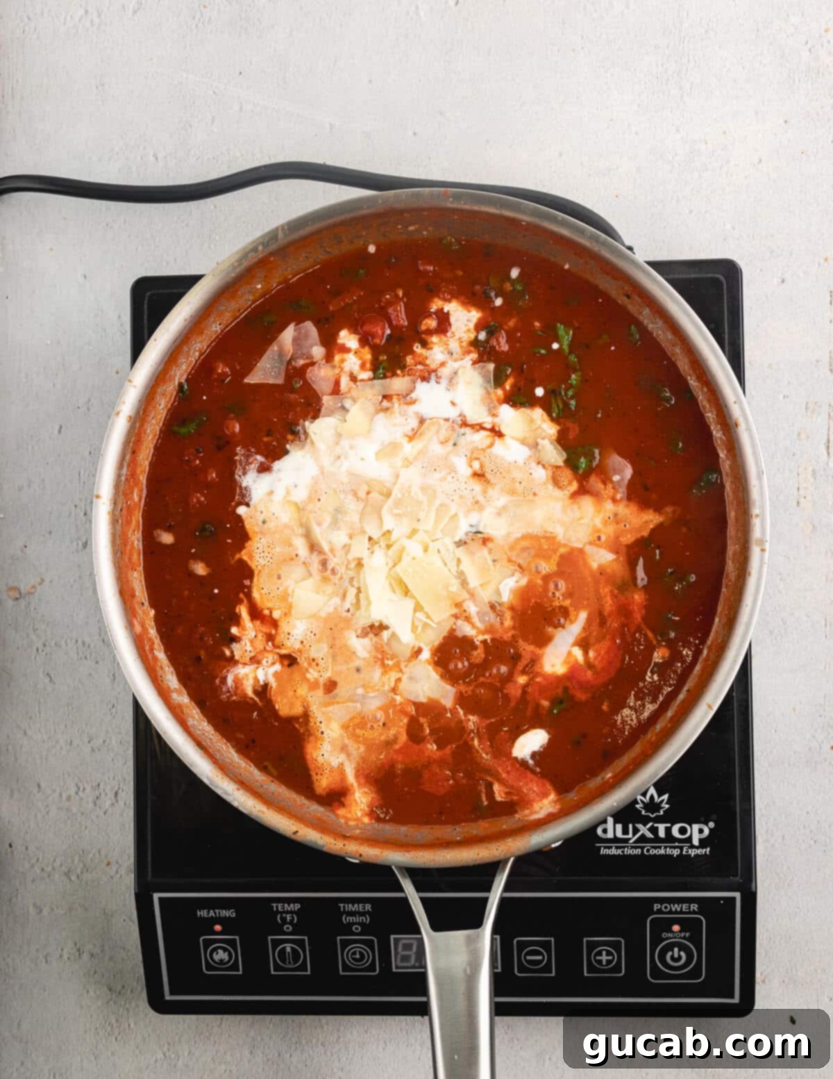 Crushed tomatoes combined with heavy cream and basil in a skillet.