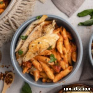 A bowl of vodka pasta with sliced chicken on top