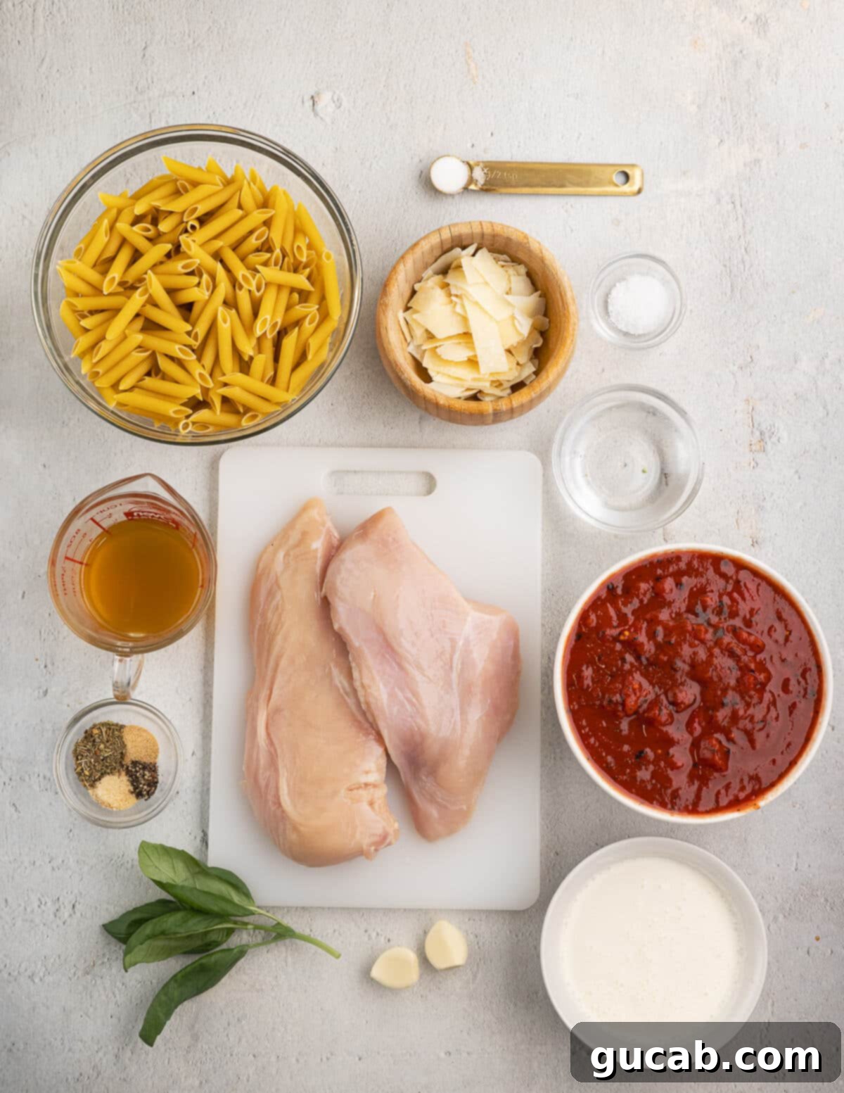The ingredients for chicken vodka pasta: pasta, parmesan, salt, chicken, spices, basil, garlic, tomatoes, heavy cream.