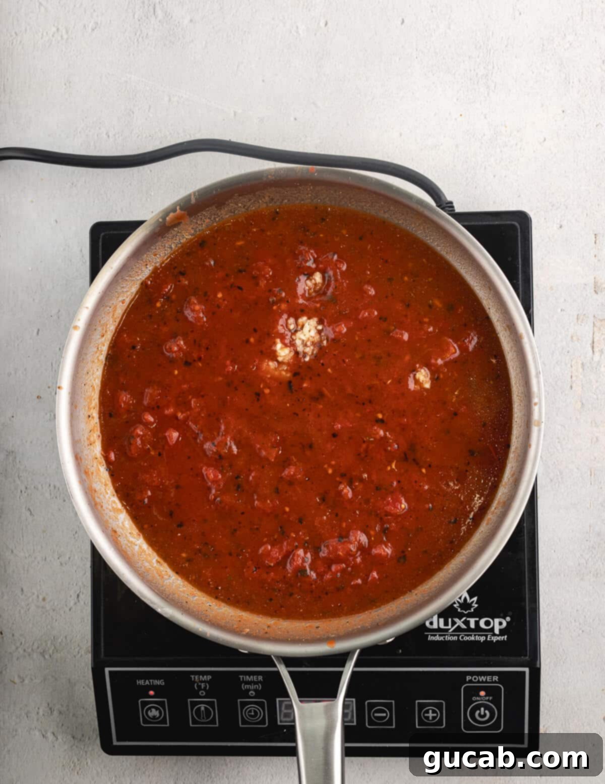 Crushed tomatoes simmering gently in a skillet.