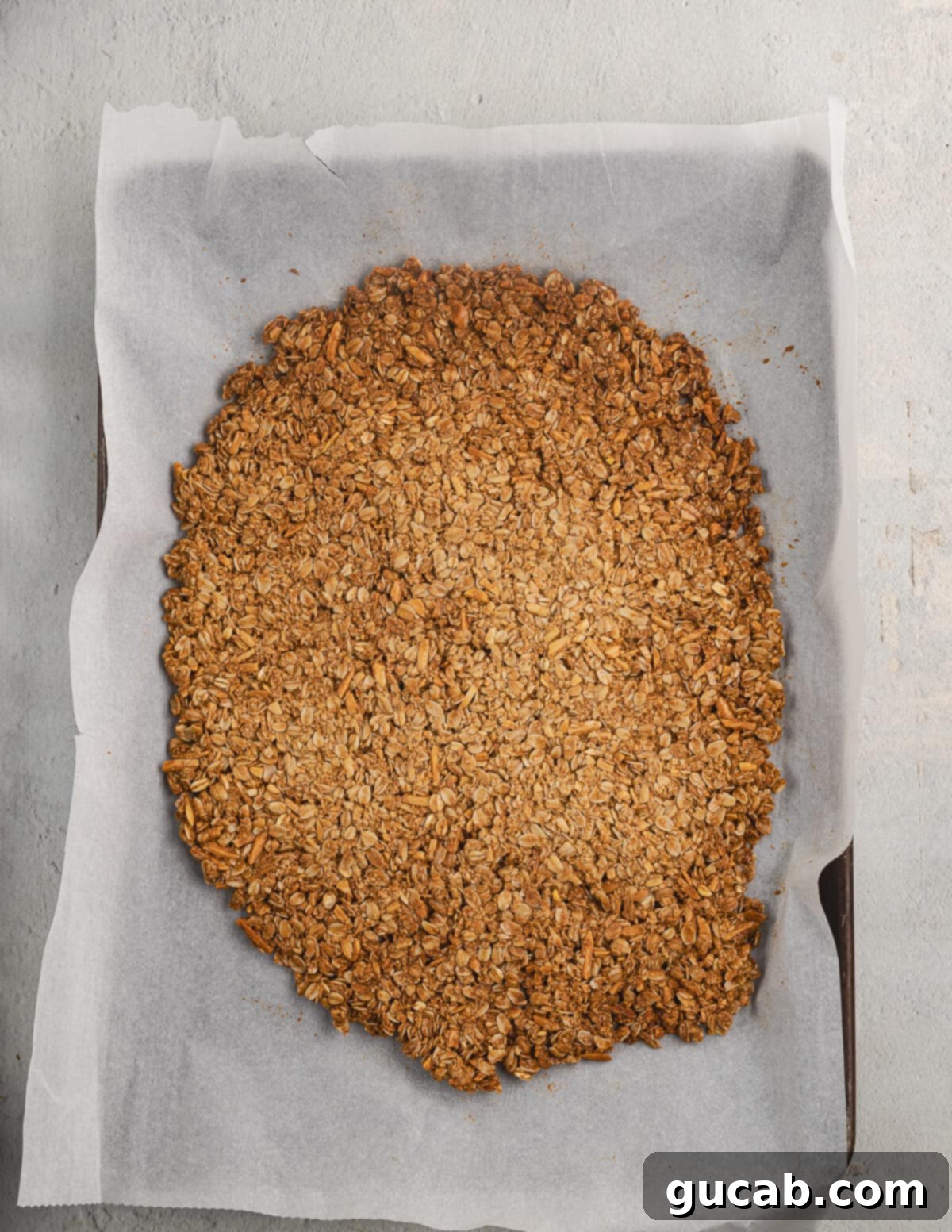 Almond Butter Crunch Granola 11 Baked almond butter granola on a parchment-lined sheet pan, straight out of the oven and golden brown