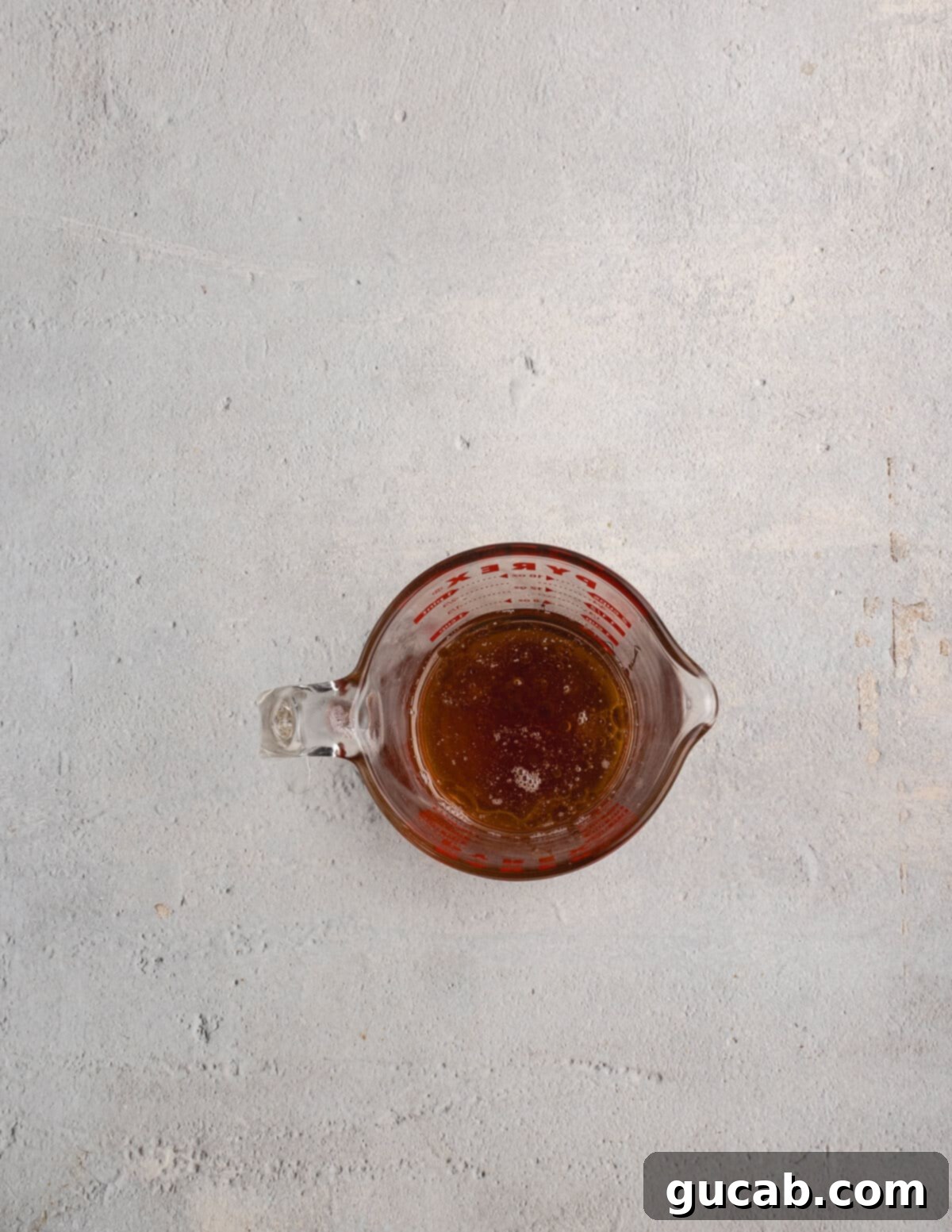 Almond Butter Crunch Granola 6 A liquid measuring cup containing maple syrup, coconut oil, and almond butter, ready to be mixed into the granola ingredients