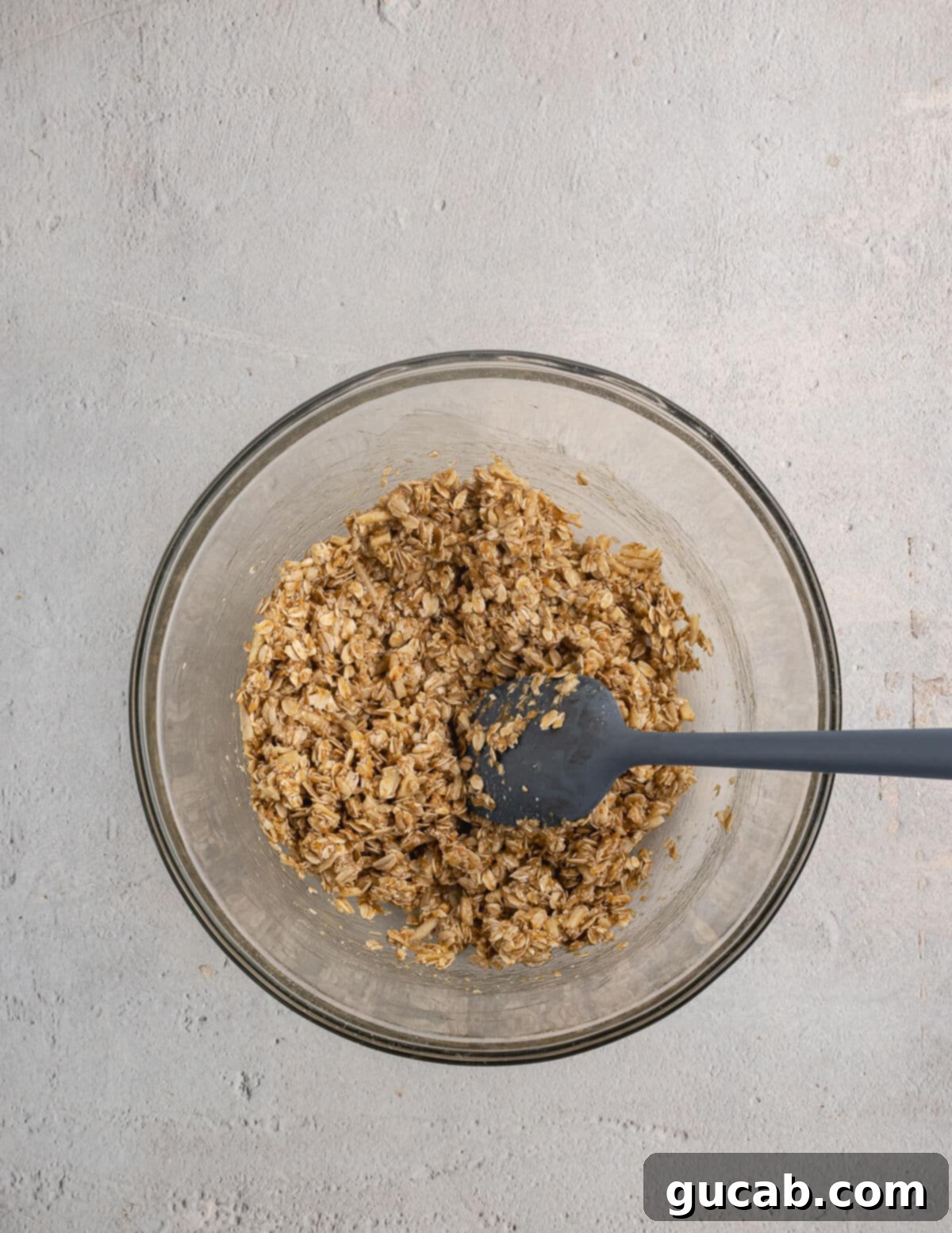 Almond Butter Crunch Granola 8 A bowl of sticky, unbaked granola mixture, ready to be spread onto a baking sheet for baking