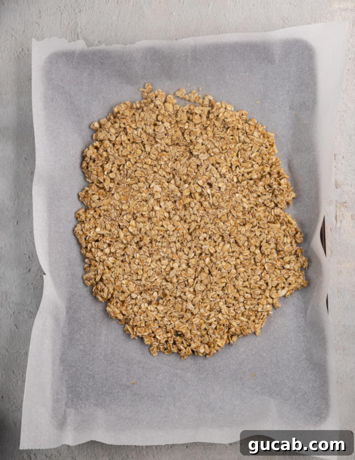 Almond Butter Crunch Granola 10 Unbaked granola mixture evenly spread out on a parchment-lined sheet pan, ready to go into the oven