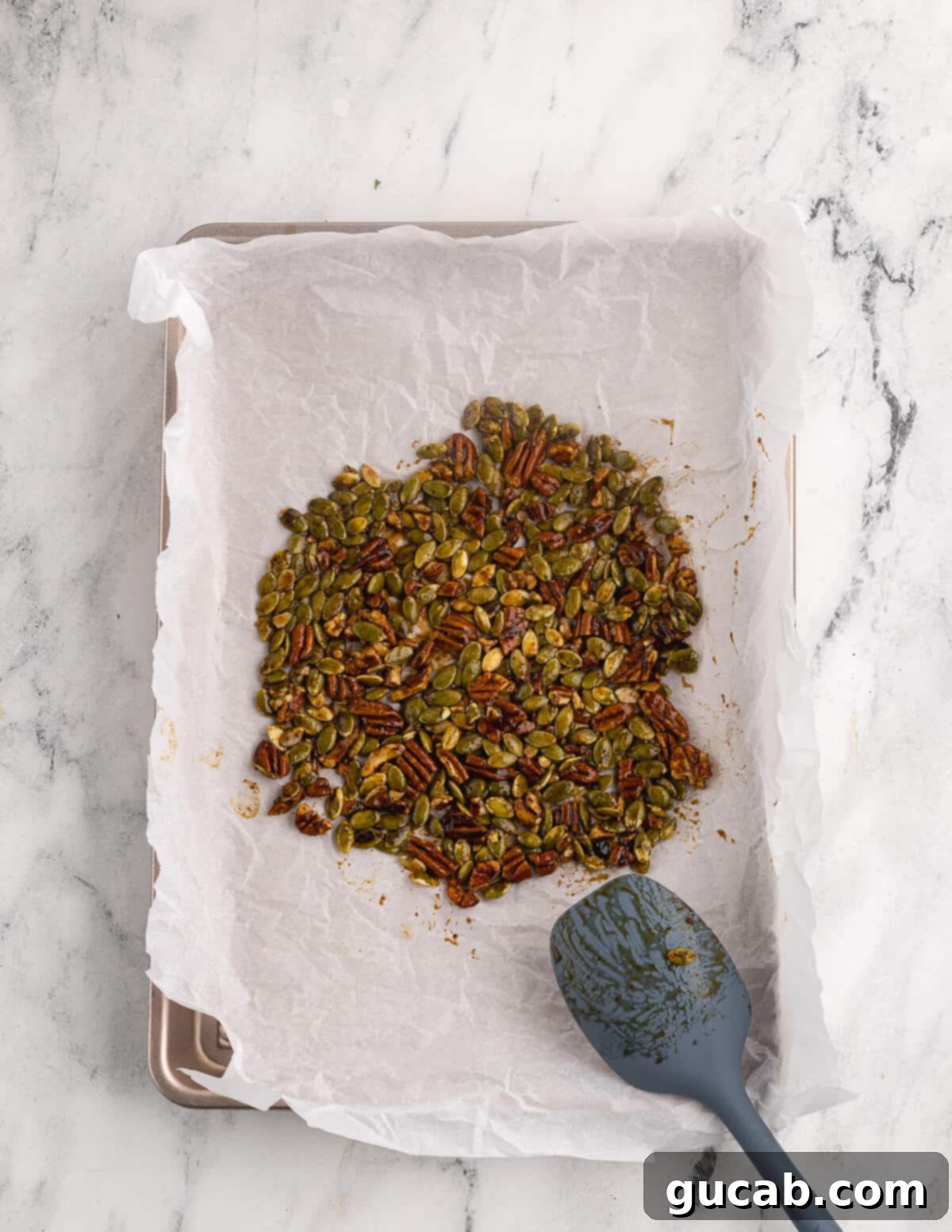 Pomegranate Pear Salad with Candied Pumpkin Seeds 5 Pepitas and chopped pecans with maple syrup spread out on a sheet pan.