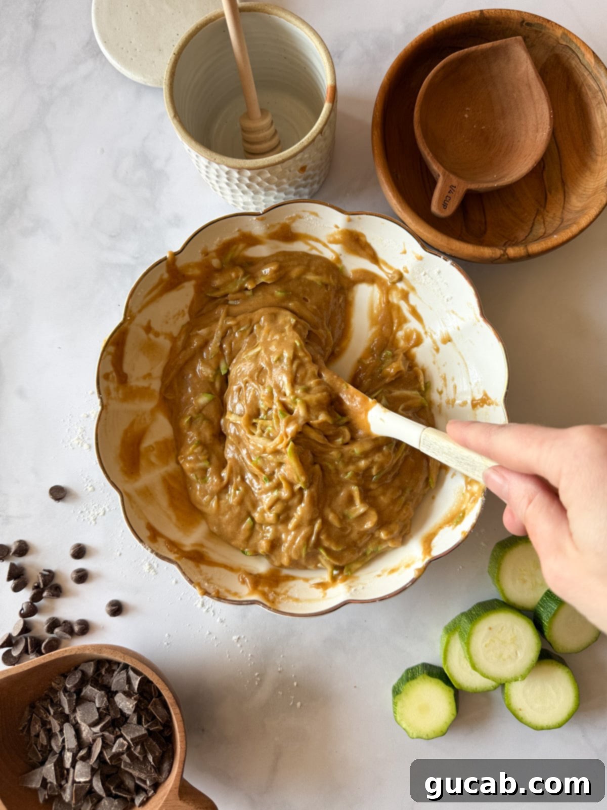 Heartwarming Zucchini Muffins 11 Stirring a bowl of zucchini muffin batter with a spatula, ensuring the zucchini is evenly distributed.
