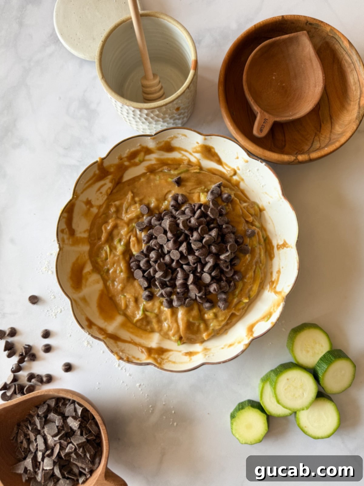 Heartwarming Zucchini Muffins 12 A bowl of zucchini muffin batter with chocolate chips on top, ready to be baked into delicious muffins.