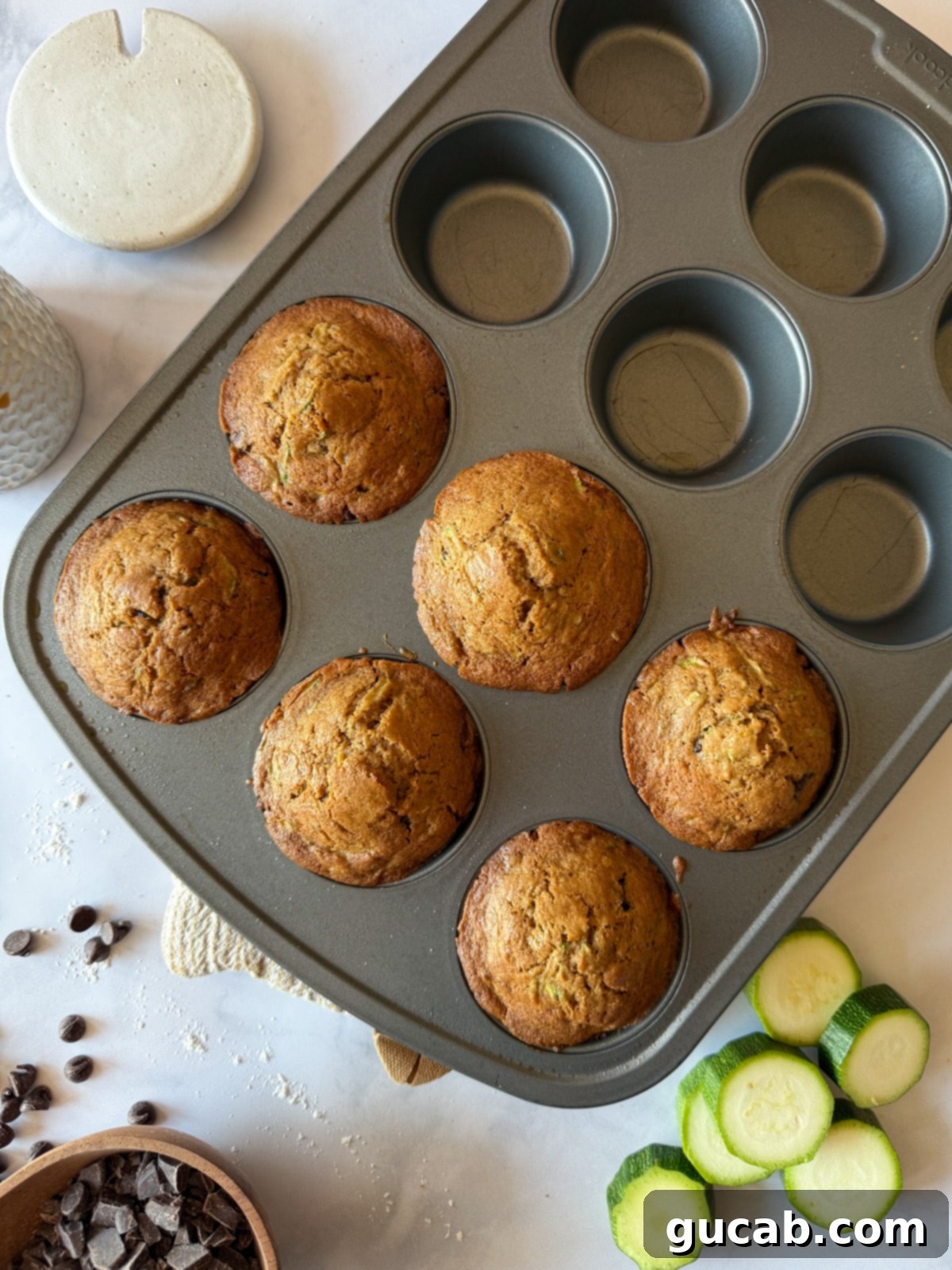 Heartwarming Zucchini Muffins 14 Baked zucchini muffins in a muffin tin, showcasing their golden-brown tops and delicious appearance.