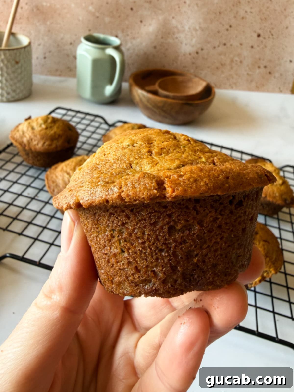 Heartwarming Zucchini Muffins 4 A hand holding a freshly baked zucchini muffin, inviting you to take a bite and experience its deliciousness.