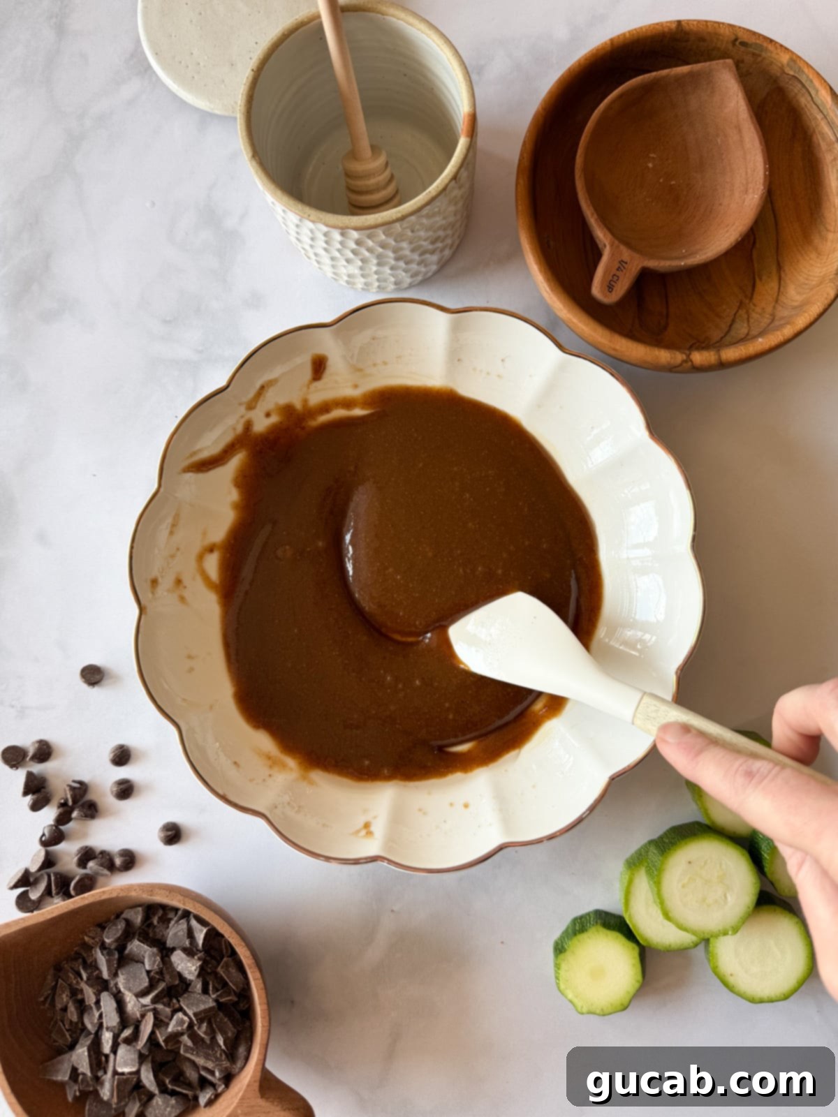 Heartwarming Zucchini Muffins 6 A bowl with maple syrup, coconut oil, and coconut sugar mixed until smooth, showcasing the emulsified base for the muffin batter.
