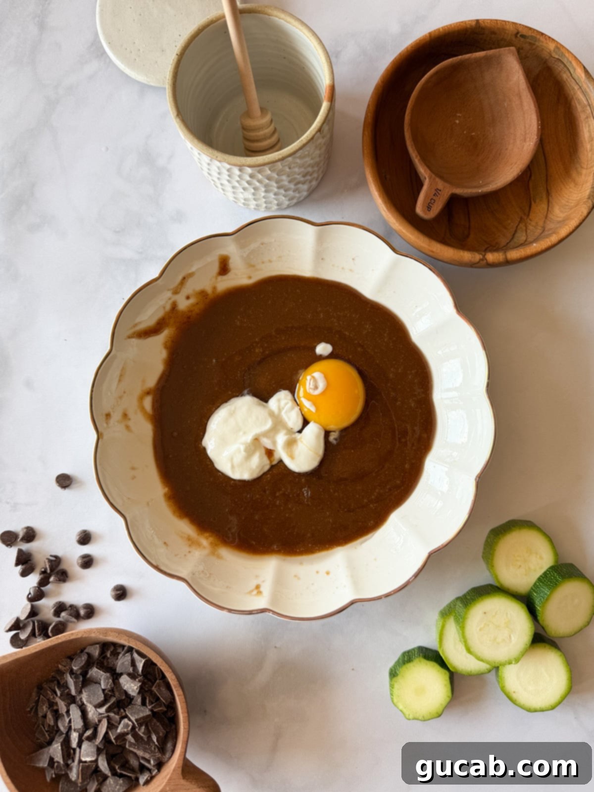 Heartwarming Zucchini Muffins 7 Maple syrup and coconut oil mixed together with Greek yogurt and an egg on top, preparing for the wet ingredients to be fully incorporated.