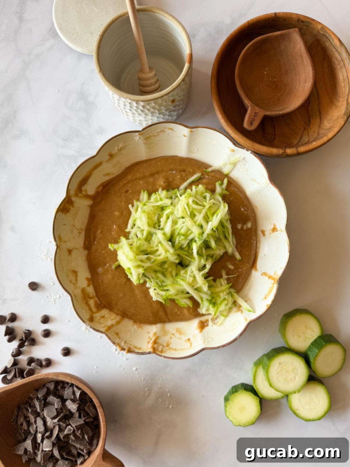 Heartwarming Zucchini Muffins 10 Zucchini muffin batter in a bowl with shredded zucchini on top, preparing for the zucchini to be mixed in.