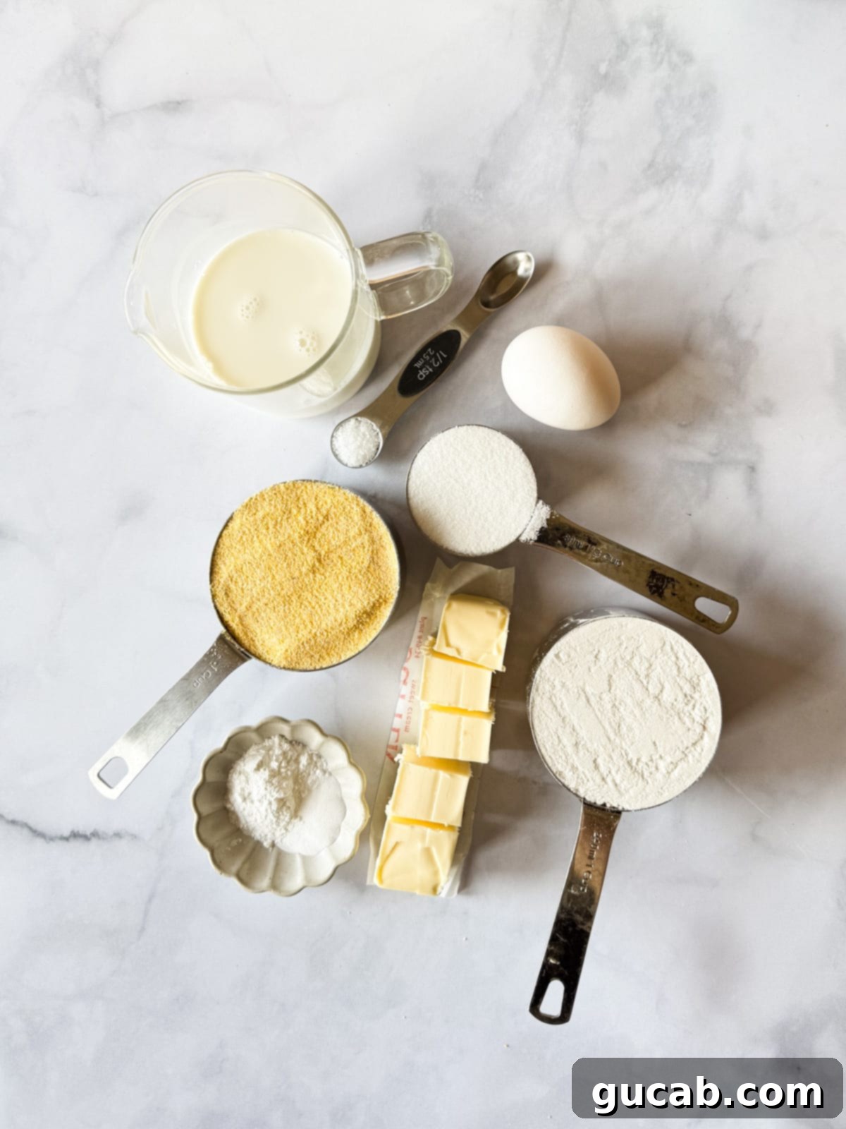 Close-up of essential ingredients for gluten-free cornbread, including gluten-free flour, cornmeal, sugar, and an egg.